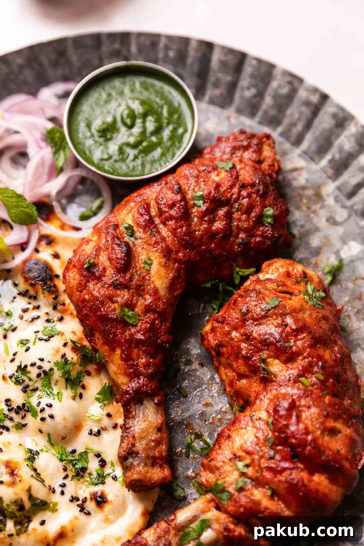 Crispy Air Fried Tandoori Chicken 2 Delicious tandoori chicken served on a plate with fresh naan, vibrant mint chutney, and sliced red onions, ready to be enjoyed.