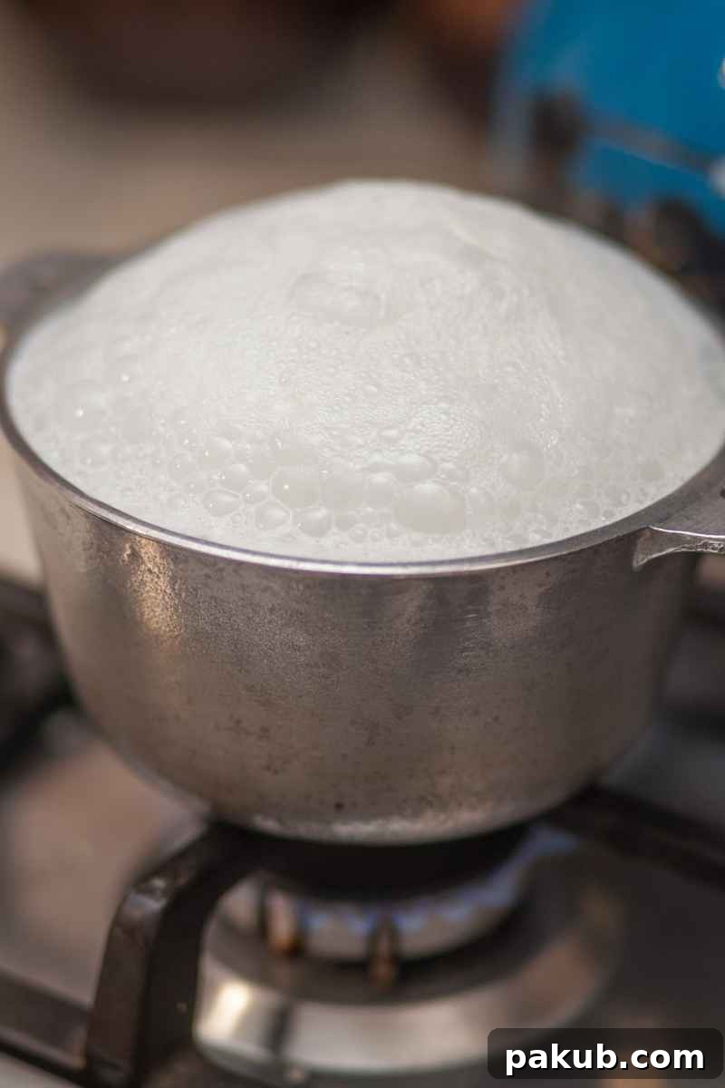 Close-up image of milk gently simmering in a saucepan, highlighting the clean edges and bottom of the pot.