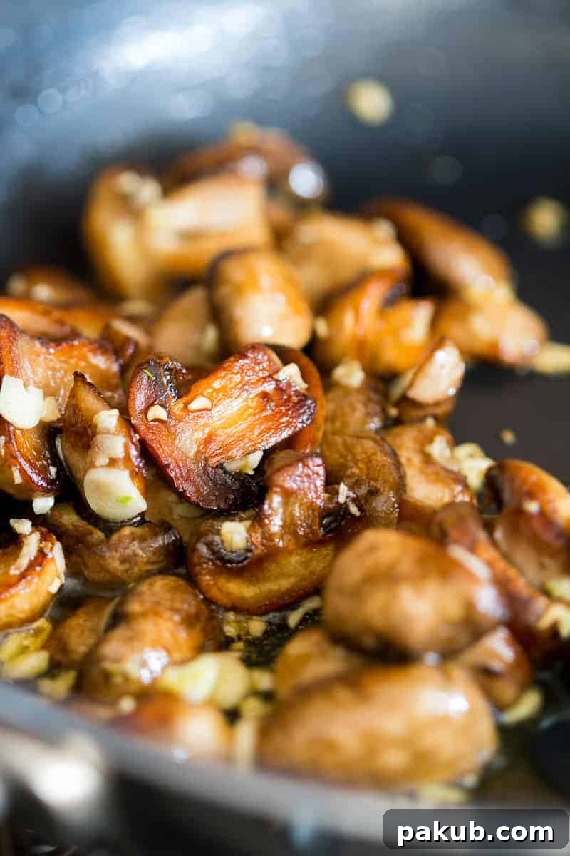 Deliciously coated spaghetti with sautéed mushrooms and garlic, perfectly seasoned and ready for a quick meal. The pasta glistens with olive oil, promising a comforting taste.