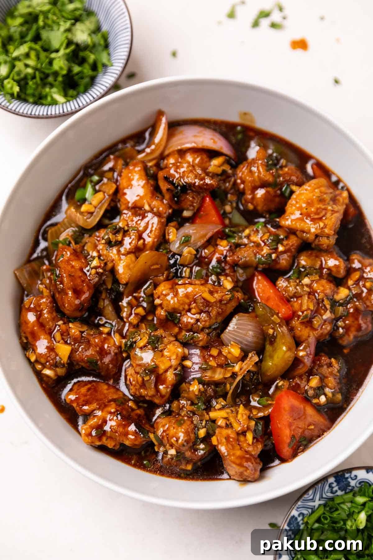 A vibrant bowl of Chicken Manchurian garnished with fresh herbs, ready to be served.