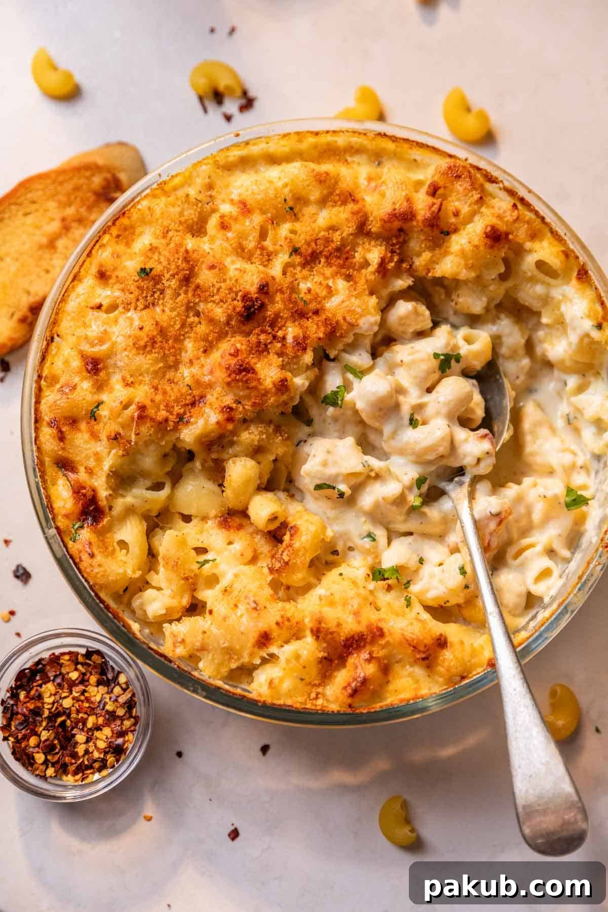 Crinkly, golden top of air fryer mac and cheese, broken into to reveal its rich, creamy interior.