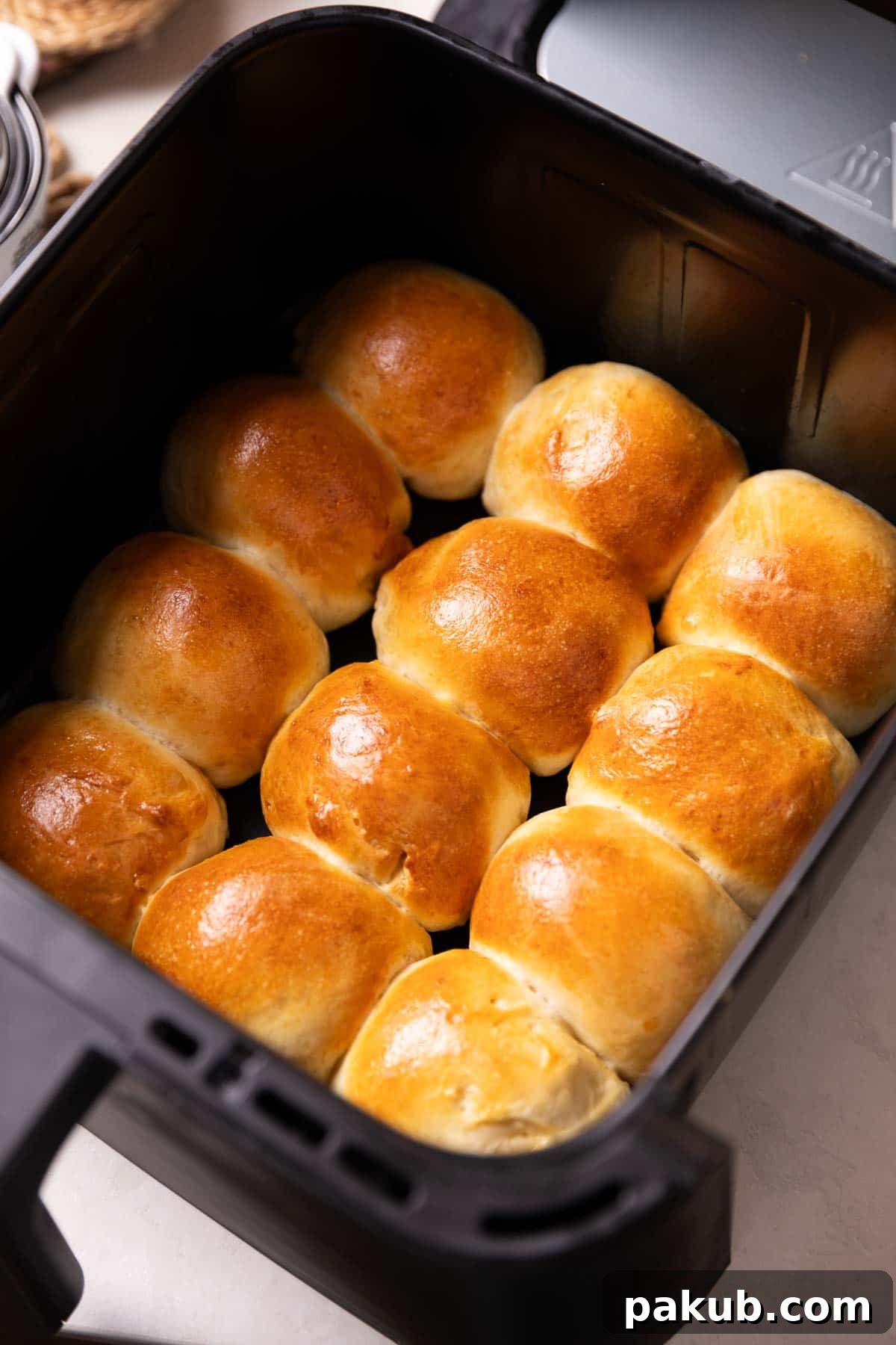 Air Frying Demystified 2 freshly baked dinner rolls in an air fryer basket, ready to be served