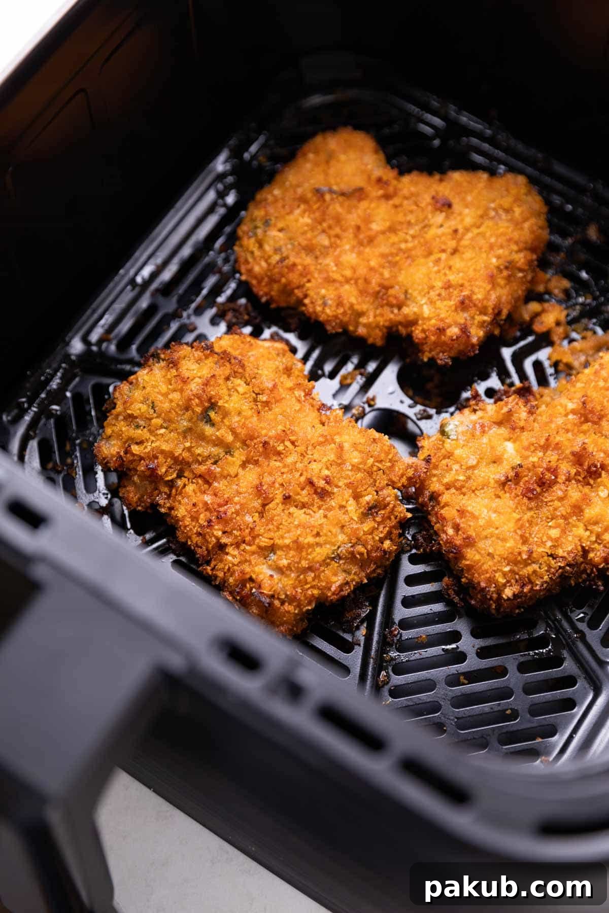 Air Frying Demystified 4 fried chicken cooking in an air fryer basket, golden brown and crispy