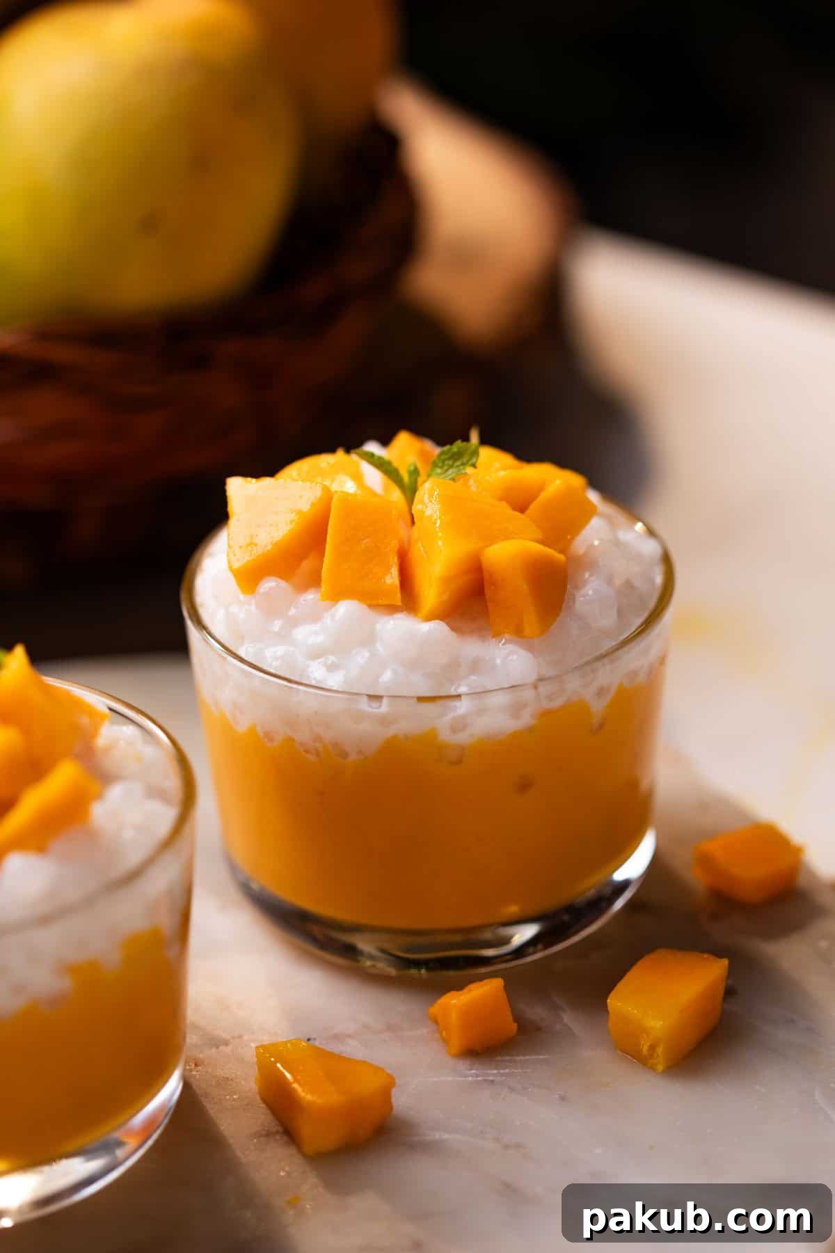 Golden Mango Sago Bliss 2 Two small glass bowls filled with creamy Mango Sago, topped with fresh mango chunks and ready to serve.