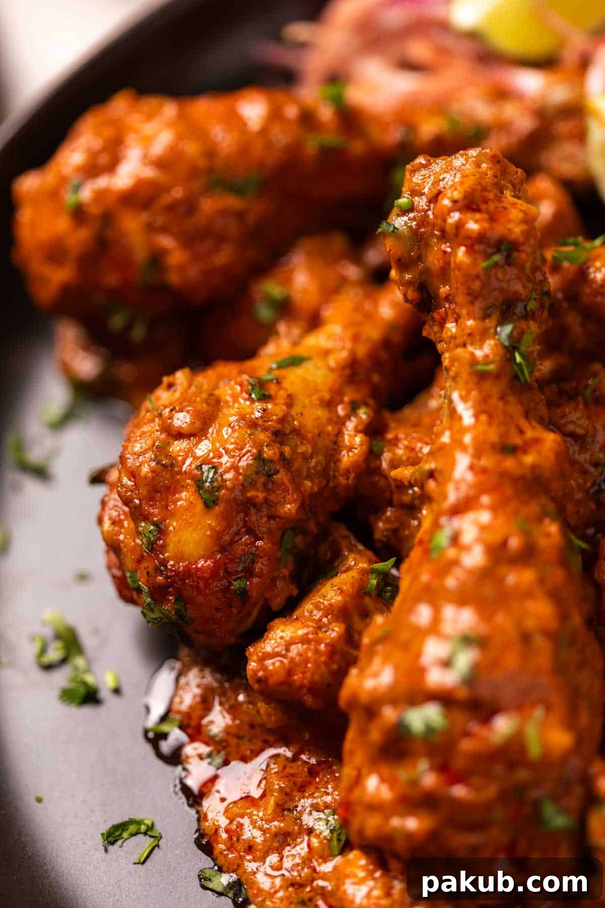 Close-up of Chicken Handi served on a black plate, garnished with fresh coriander leaves.