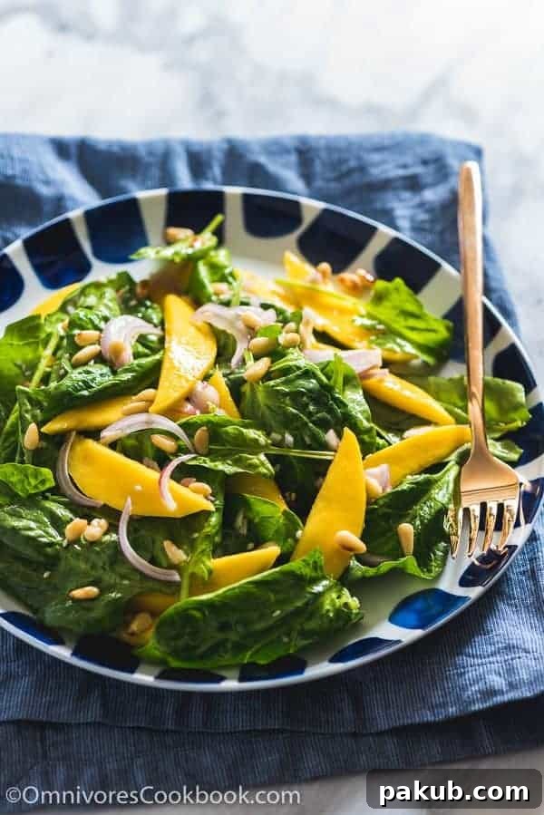 A collection of 13 insanely delicious savoury mango recipes that are sure to blow your mind if you've always had mangoes in sweet dishes. These recipes combine the juicy sweetness of mangoes with savoury ingredients to create a dish that's truly stellar and unforgettable! #spring #mango #recipes #easter #summer #fruit A refreshing Spinach Mango Salad served in a stylish black and white bowl, accompanied by a fork, ready for a healthy and flavorful meal.