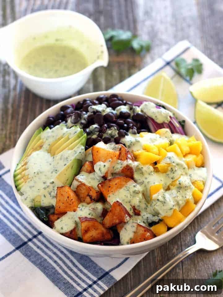 A collection of 13 insanely delicious savoury mango recipes that are sure to blow your mind if you've always had mangoes in sweet dishes. These recipes combine the juicy sweetness of mangoes with savoury ingredients to create a dish that's truly stellar and unforgettable! #spring #mango #recipes #easter #summer #fruit Colorful Mango Sriracha Potato Veggie Bowls, generously topped with a rich dressing, with additional dressing thoughtfully placed on the side.