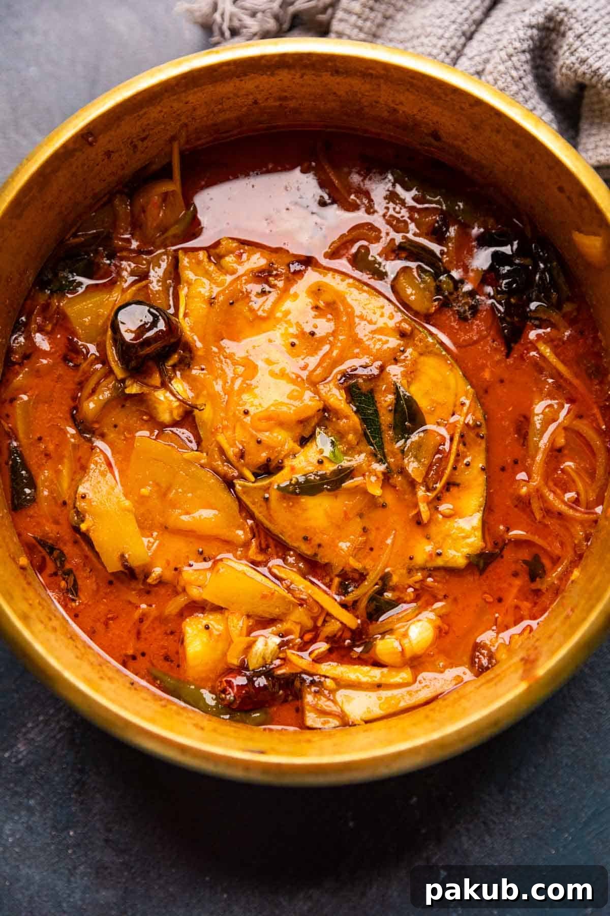 Beyond Sweet: Irresistible Savory Mango Recipes 3 A rich and aromatic Raw Mango Fish Curry, traditionally served in a rustic brass pot, showcasing the vibrant colors and textures of this Keralan delicacy.