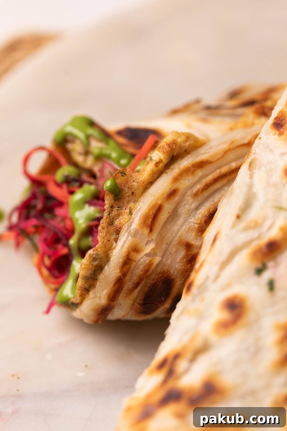 close up image of rolled up anda paratha to show its flaky texture and filling