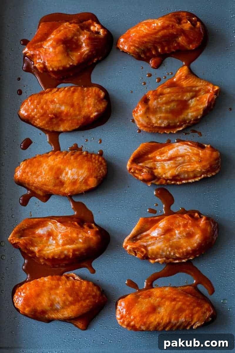 A close-up of shiny, spicy Korean Baked Gochujang Chicken Wings on a baking tray.