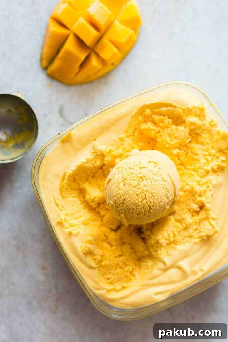 Three scoops of delicious homemade mango cheesecake ice cream in a bowl, showcasing its creamy texture and vibrant color.