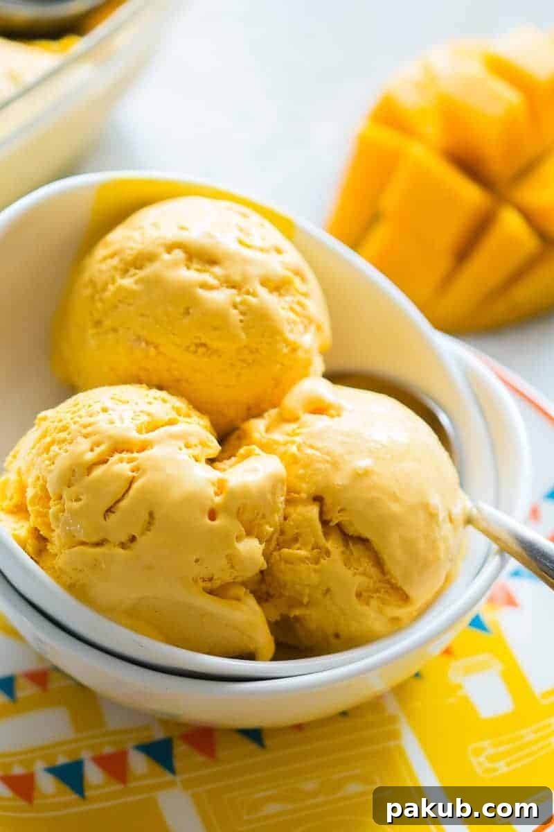 Overhead shot of creamy mango cheesecake ice cream with a spoon, ready to be enjoyed.