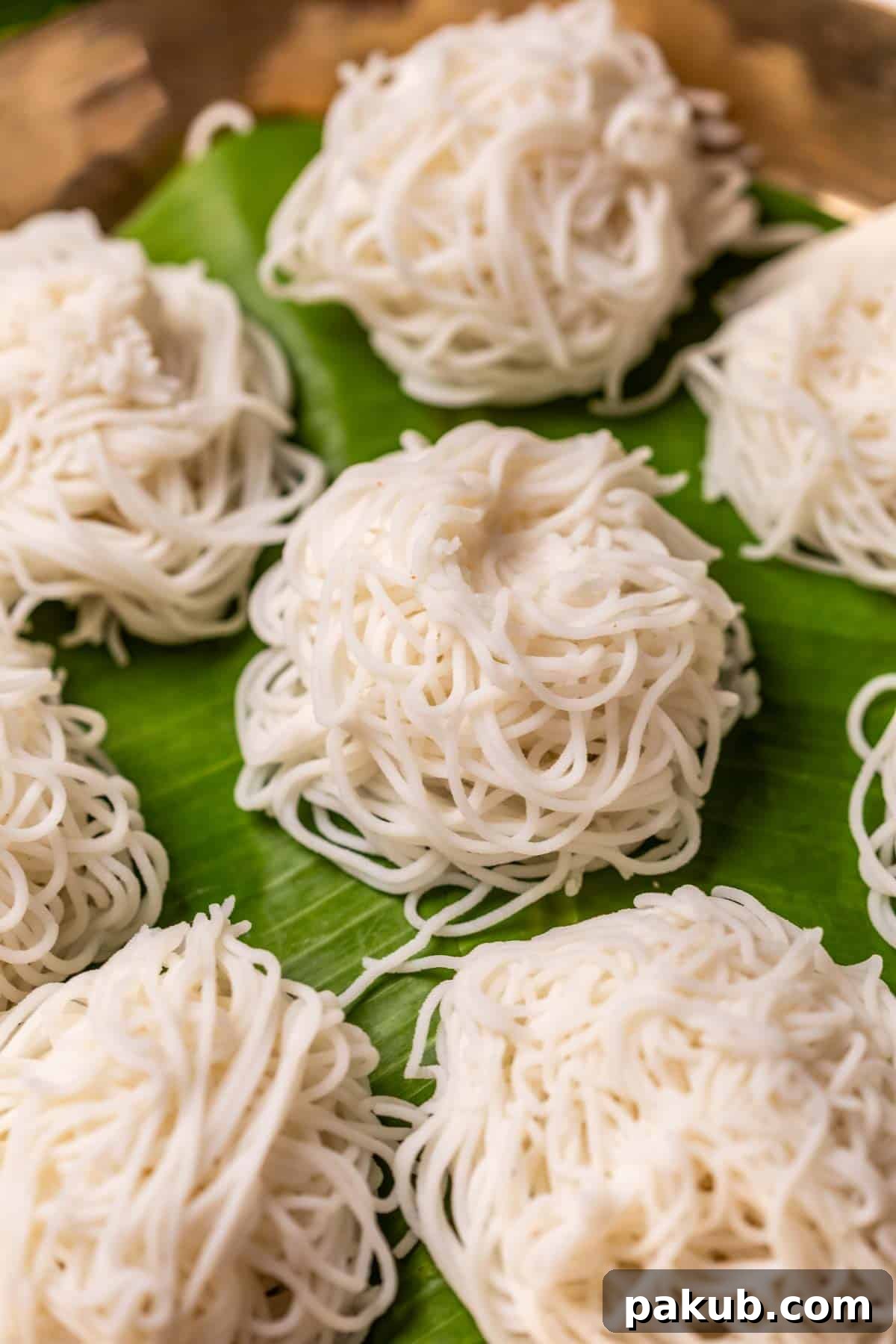 Feathery Steamed Rice Nests 4 A close-up of fluffy Rice Idiyappams on a banana leaf, showcasing their intricate, delicate strands