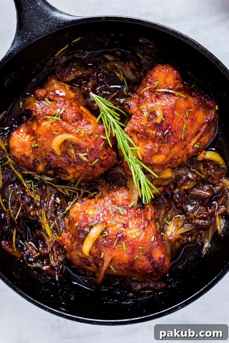 Crispy, golden-brown Caramelized Onion Rosemary Chicken Thighs in a cast iron skillet, garnished with fresh rosemary. An insanely delicious, one-pan, gluten-free recipe that takes only 30 minutes to make.