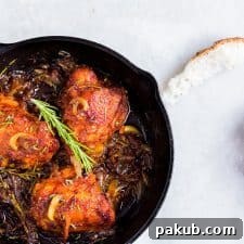 Chicken thighs garnished with rosemary in a black skillet.