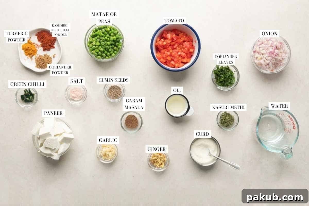 Velvety Matar Paneer Delight 3 A vibrant flat lay of all fresh ingredients required for making Matar Paneer, including paneer cubes, green peas, tomatoes, onions, ginger, garlic, and various Indian spices.