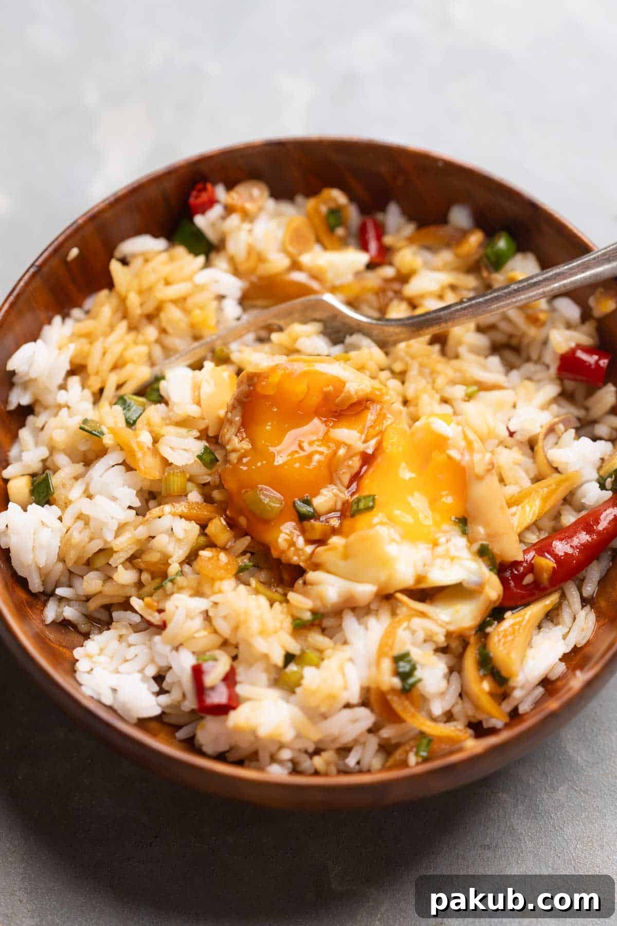 An image of Mayak Eggs poured over steamed rice and served in a wooden bowl with a spoon