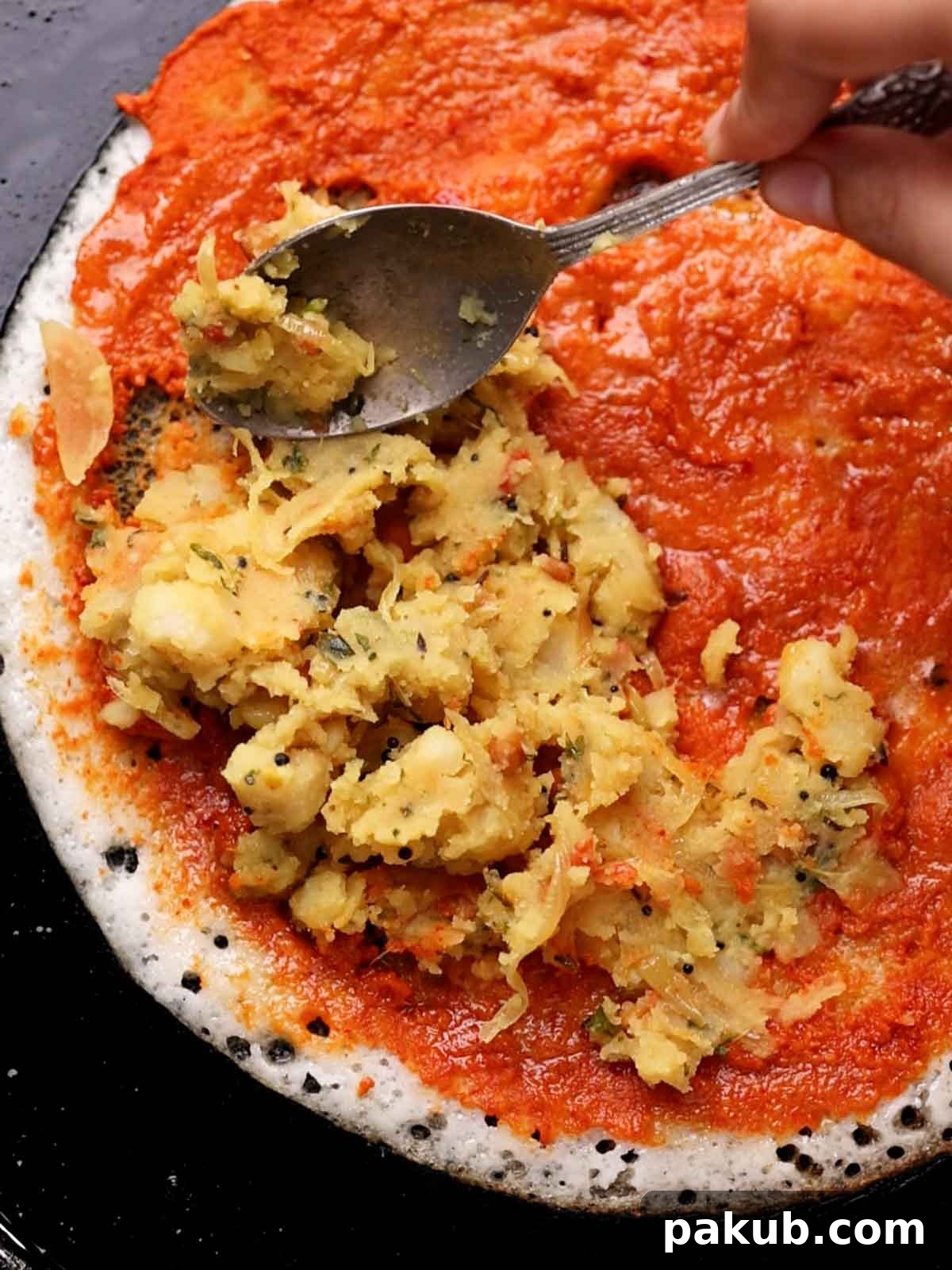 Aloo filling being spread on the dosa
