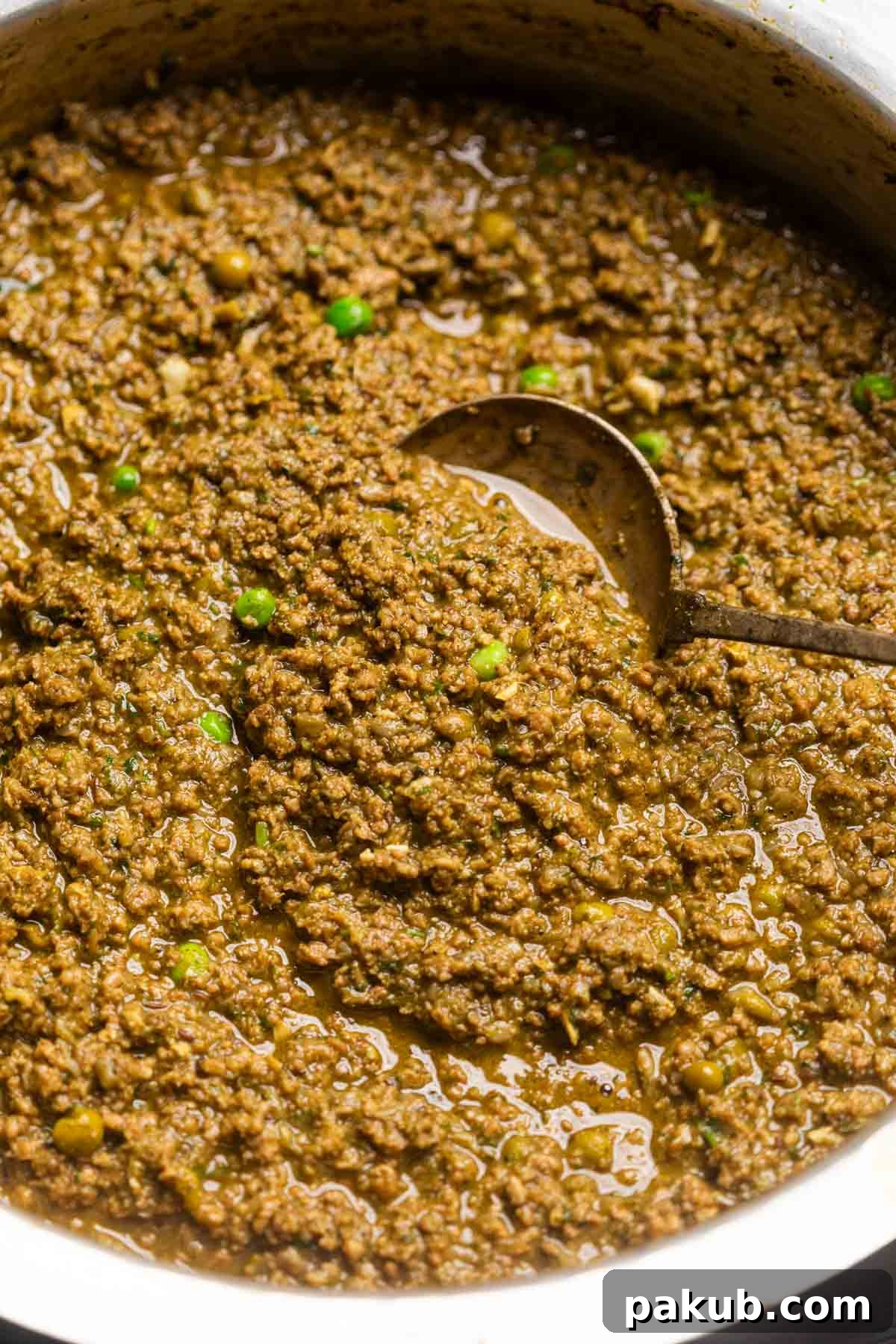 Rich green keema masala simmering in a traditional copper kadai, with a ladle resting inside, showcasing its creamy texture.