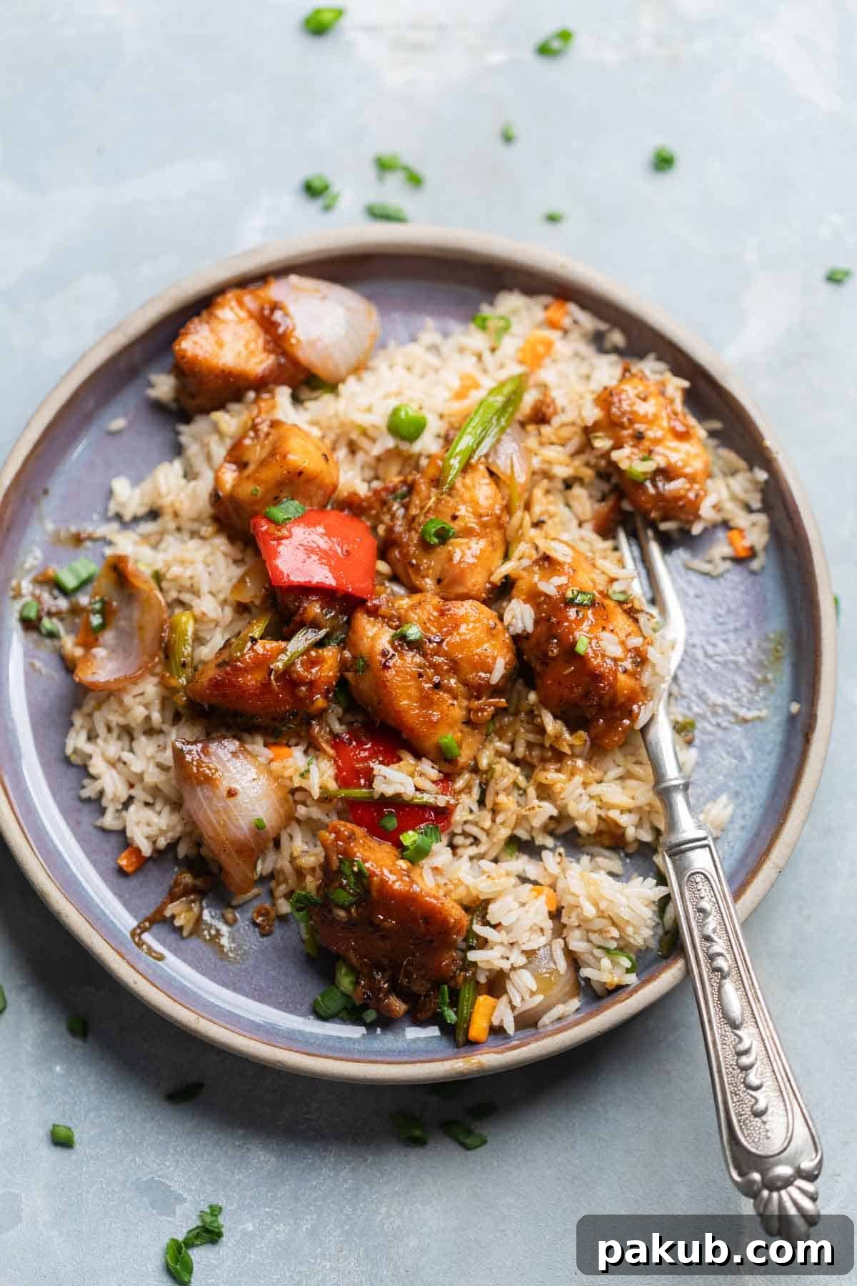 Bold Black Pepper Chicken 5 Black Pepper Chicken served over a bed of white rice on a plate, garnished with spring onions.