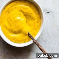 A beautifully presented white bowl filled with the creamy Blender Mango Mustard Dipping Sauce, garnished lightly and ready to be enjoyed with various snacks.