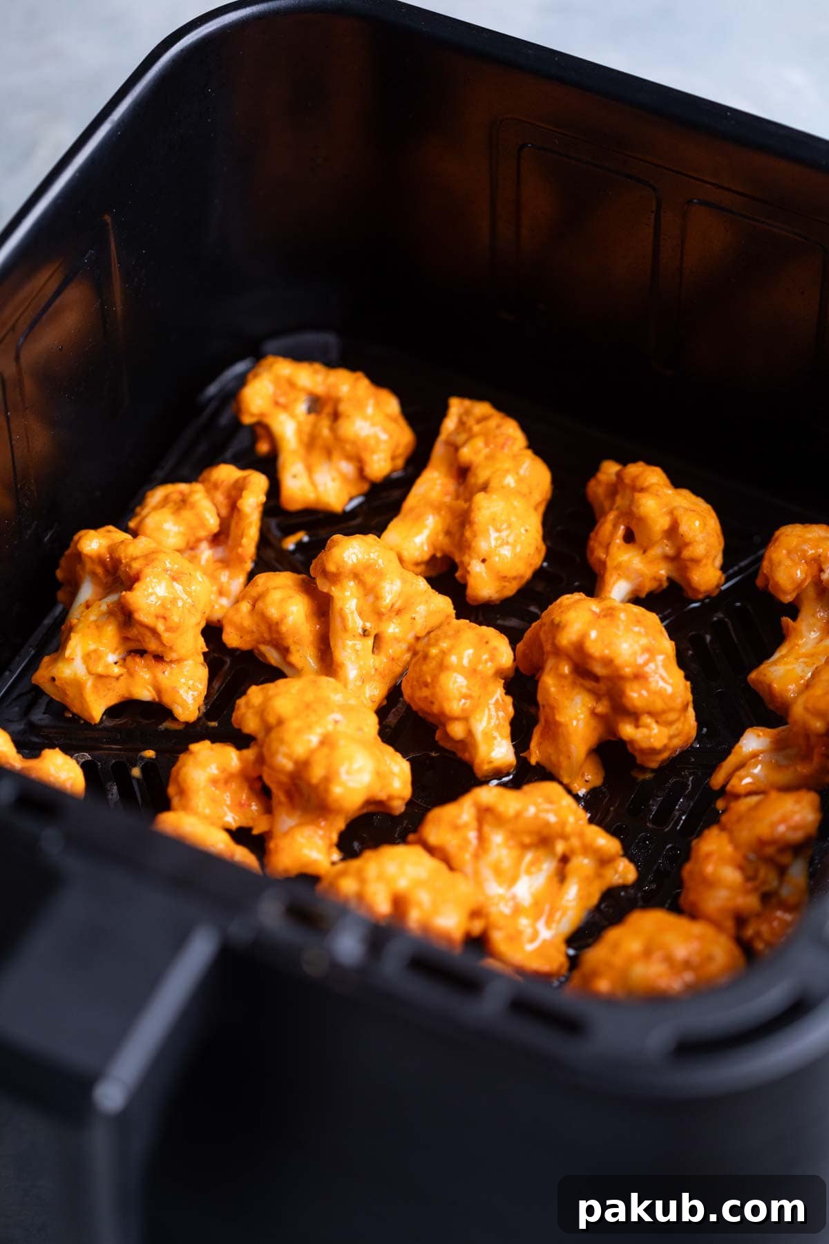 Crispy Air Fryer Bang Bang Cauliflower 4 marinated bang bang cauliflower florets arranged in the air fryer basket ready to be cooked