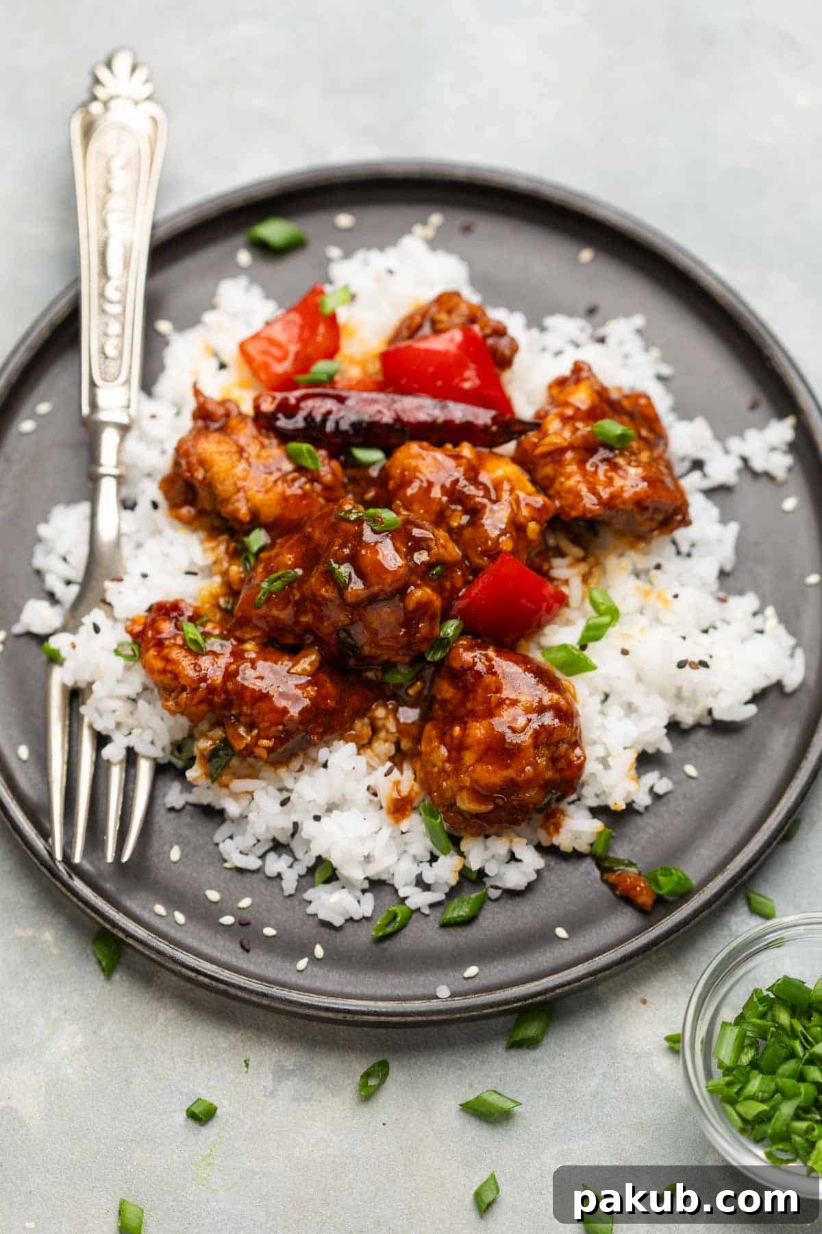 Close-up of General Tso's chicken garnished with sesame seeds and spring onions, ready to be served
