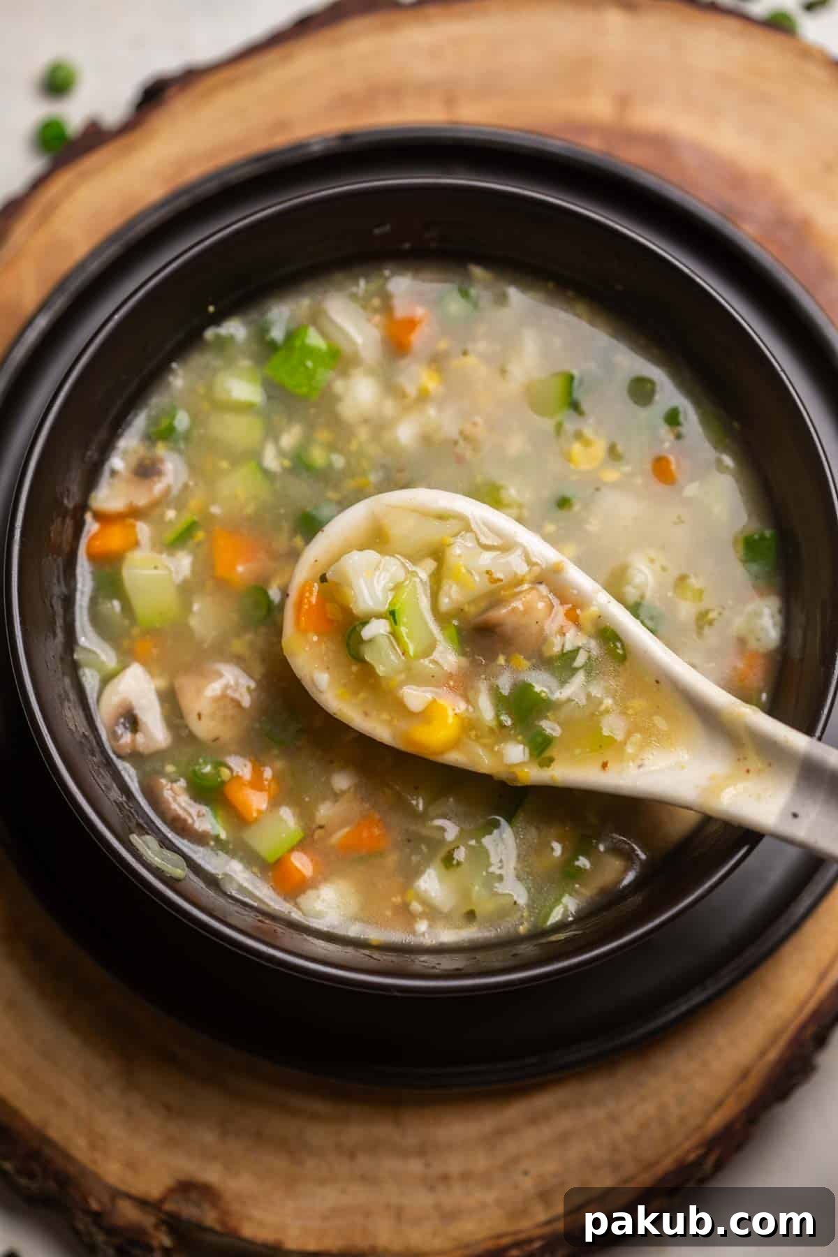 A steaming bowl of vibrant Eight Treasure Soup, filled with colorful vegetables, served with a white soup spoon, ready to be enjoyed as a wholesome and comforting meal.