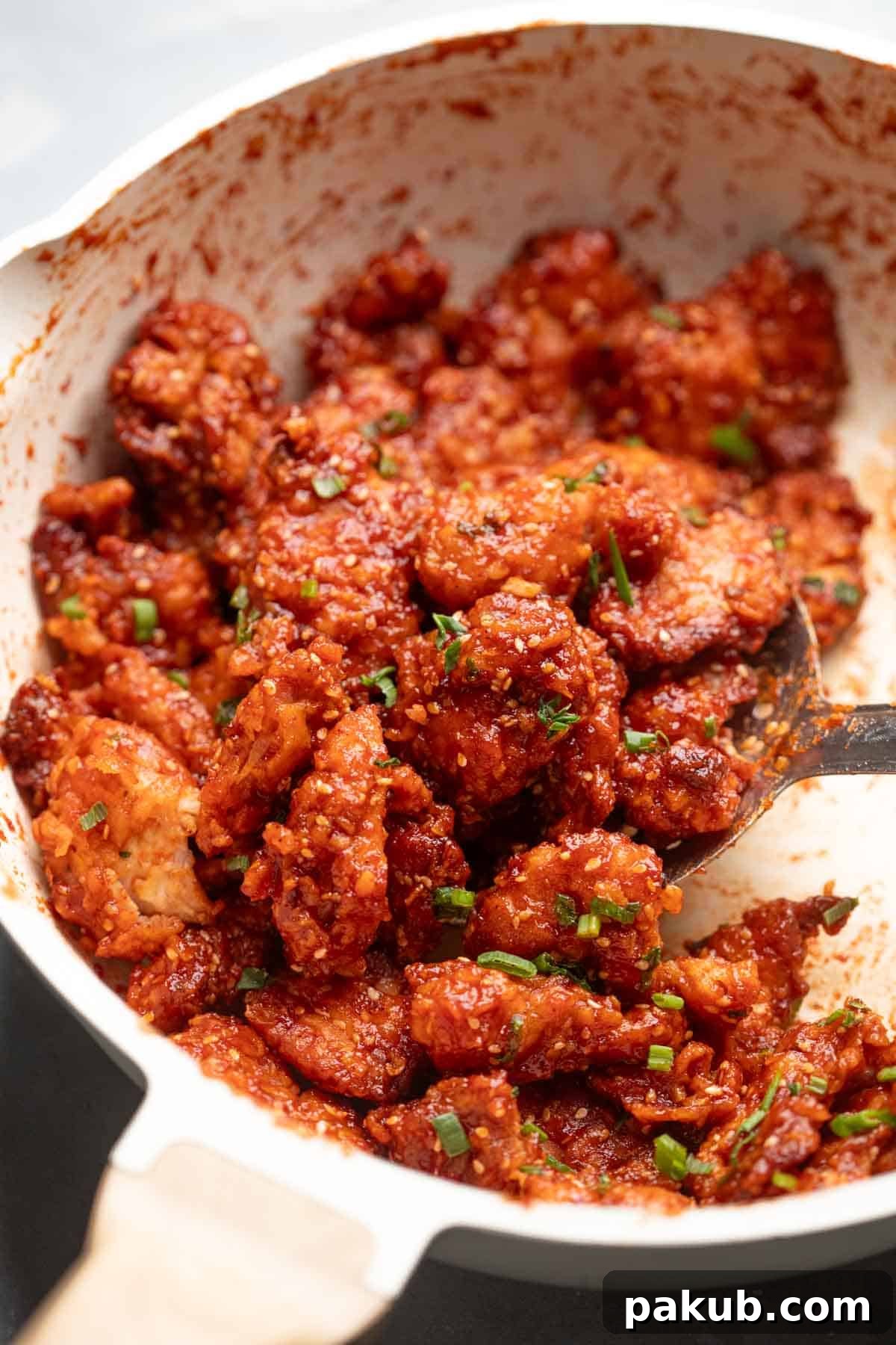 Honey garlic chicken being tossed in a pan, showcasing its glossy, sticky coating