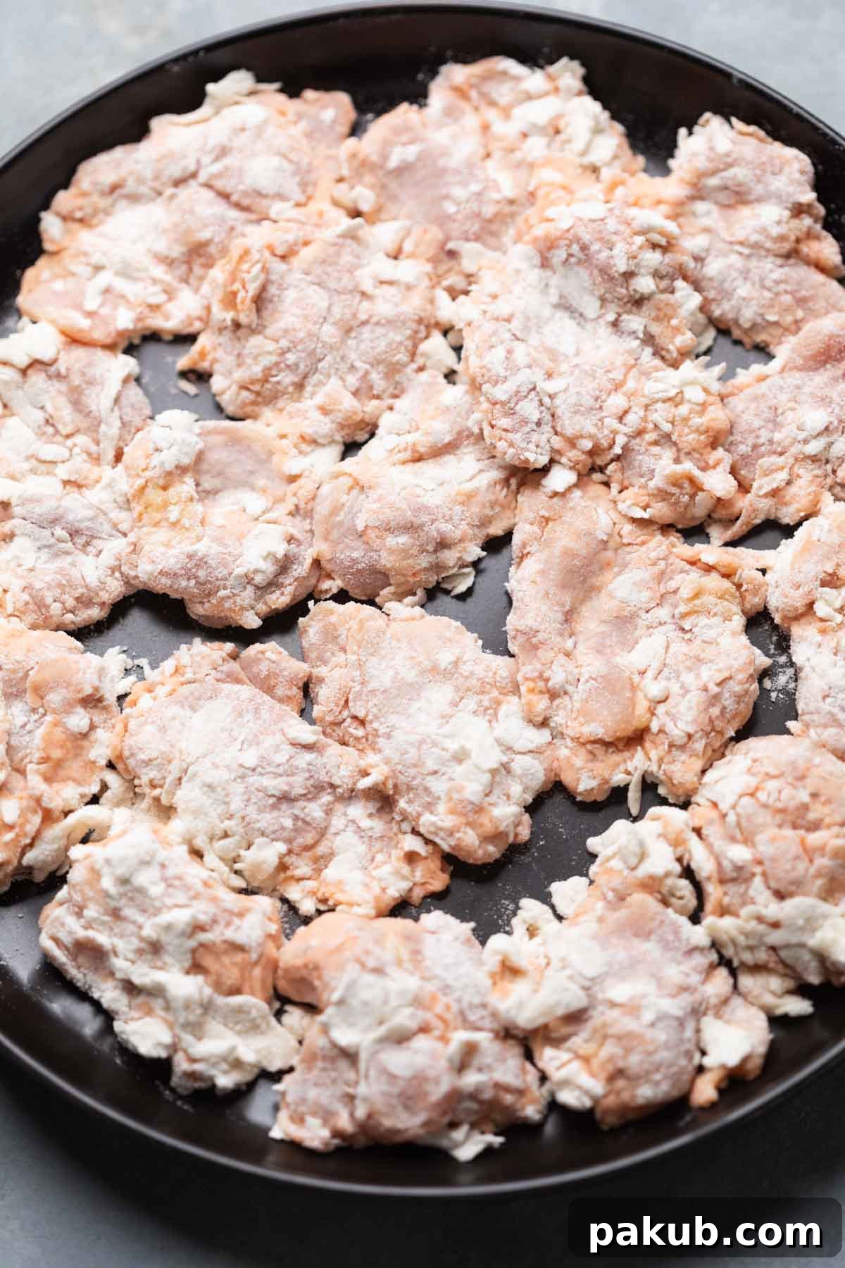 Dredged chicken thighs coated in flour, ready to be air-fried or deep-fried