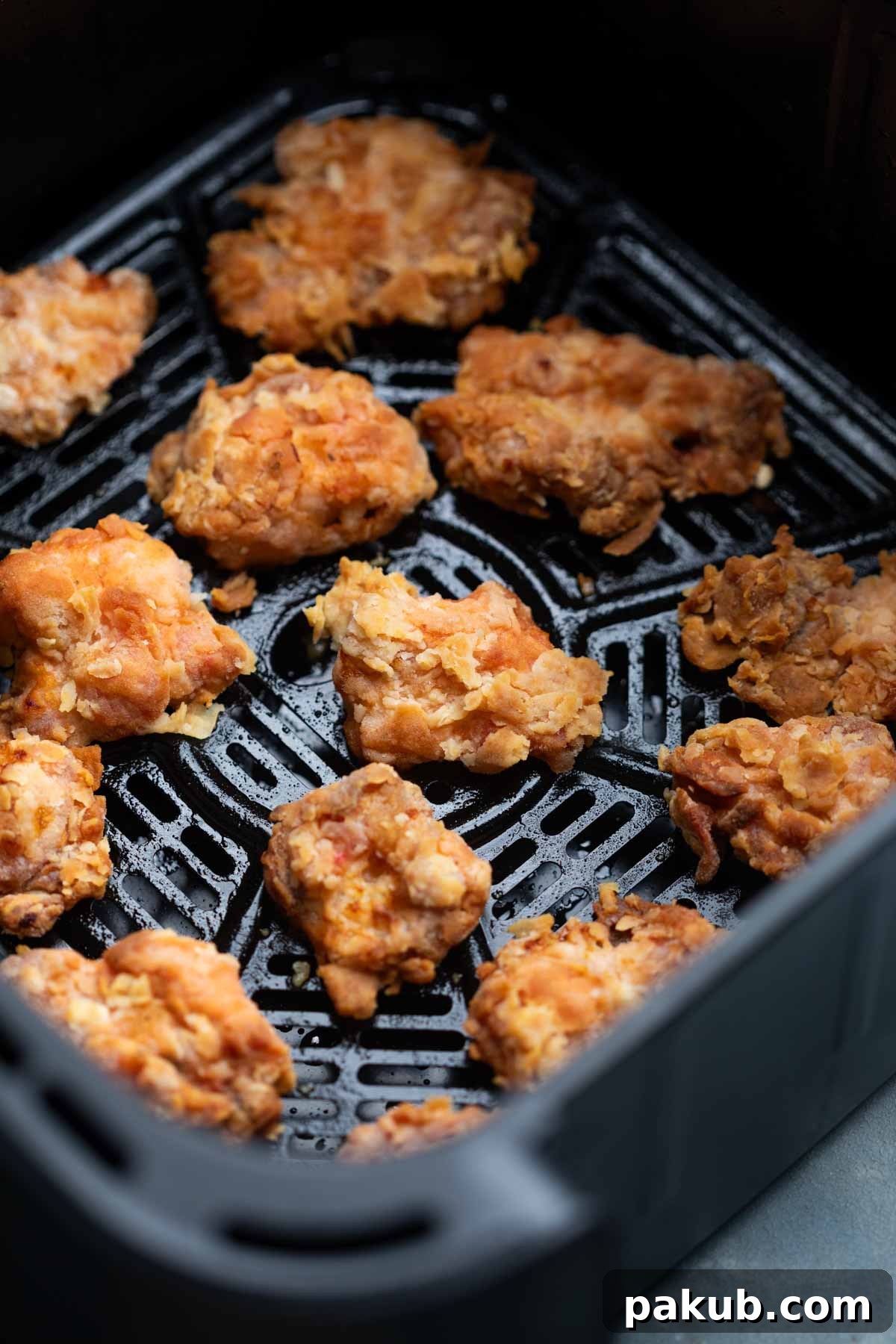 Crispy air-fried chicken pieces in an air fryer basket, showcasing their golden-brown texture