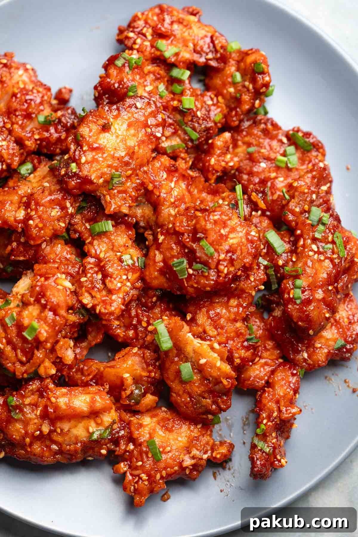 Crispy, glossy, and sticky honey garlic chicken served beautifully on a white plate with garnishes