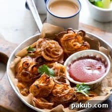 Crispy Baked Onion Pakodas (Fritters) garnished with coriander and served with sauce and chai.