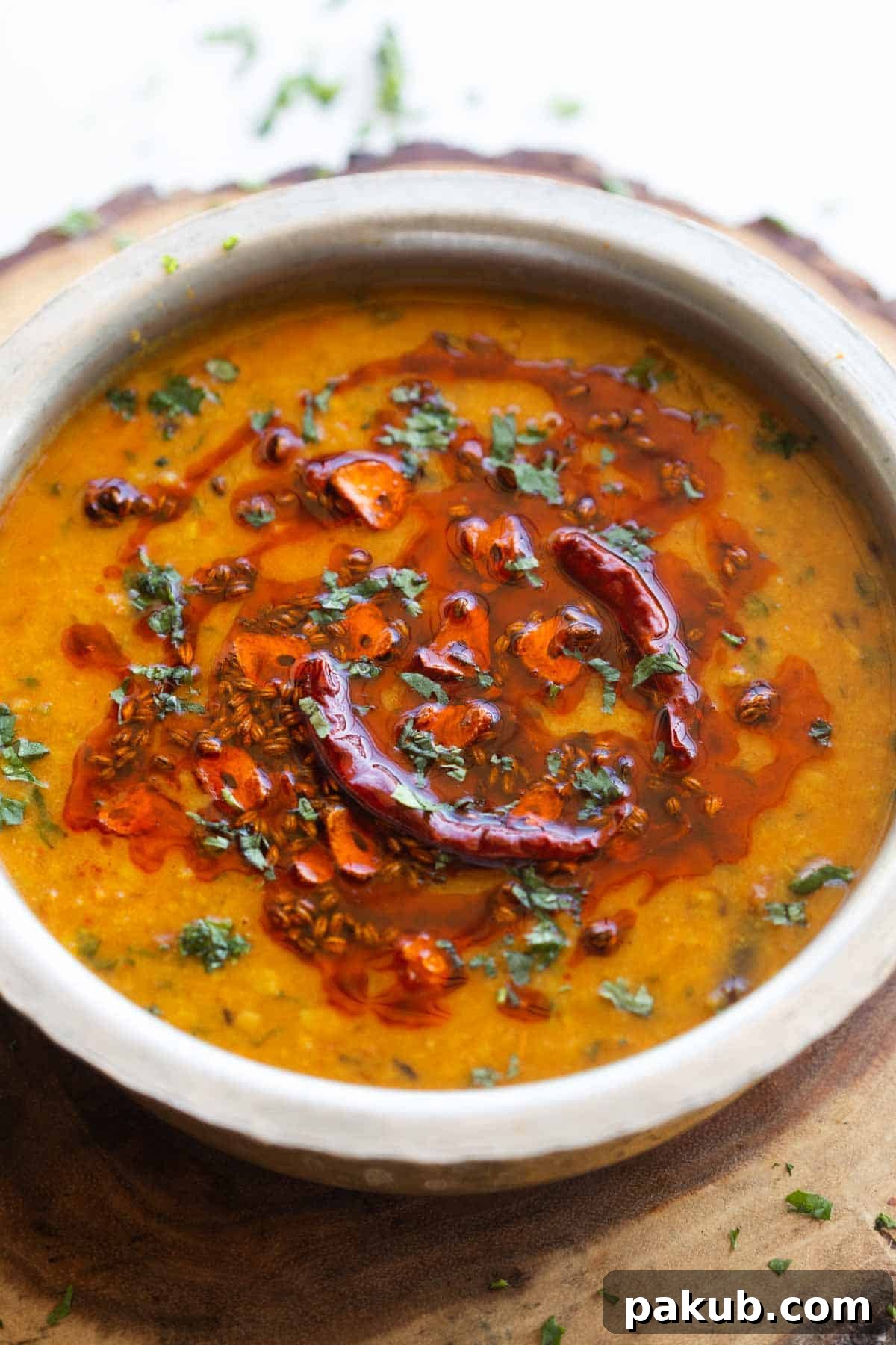 Spiced Golden Lentils 2 Rich and creamy Dal Tadka served in a traditional handi style vessel, garnished with fresh coriander.