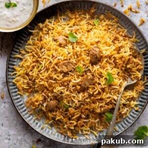 A plateful of mushroom biryani with a spoon on the side and a bowl of raita