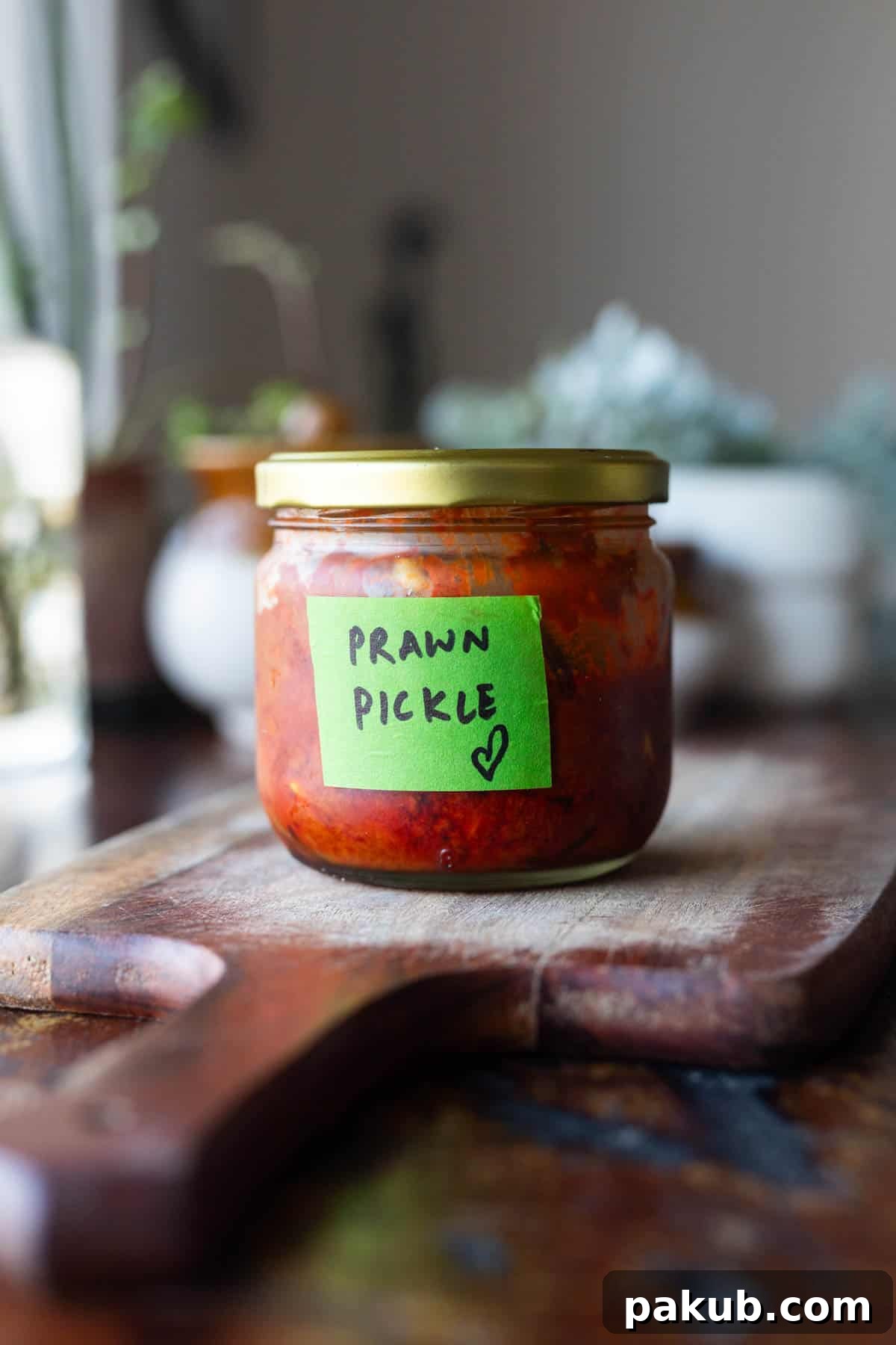 A bottle of Mangalorean prawn pickle labelled with green tape, ready for storage and consumption.