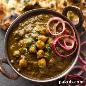 A bowl of chole palak served along with onion rounds and naan