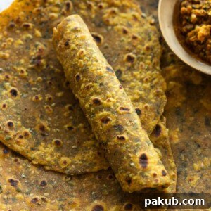 Soft and Spiced Methi Thepla 5 close up image of freshly made methi thepla with one rolled to showcase it's soft texture