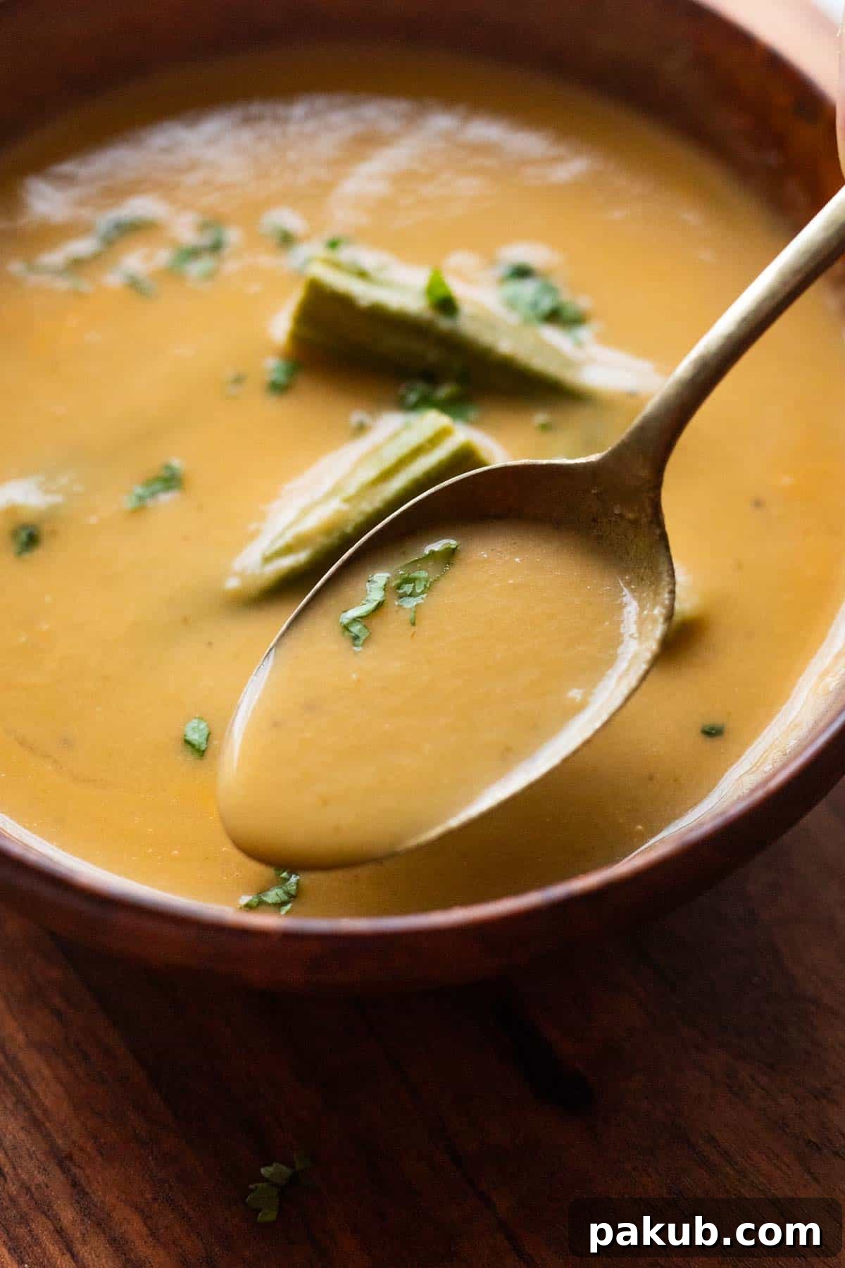 Nourishing Moringa Green Soup 3 a close up image of drumstick soup garnished with boiled drumsticks and coriander leaves