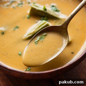Nourishing Moringa Green Soup 4 a close up image of drumstick soup garnished with boiled drumsticks and coriander leaves