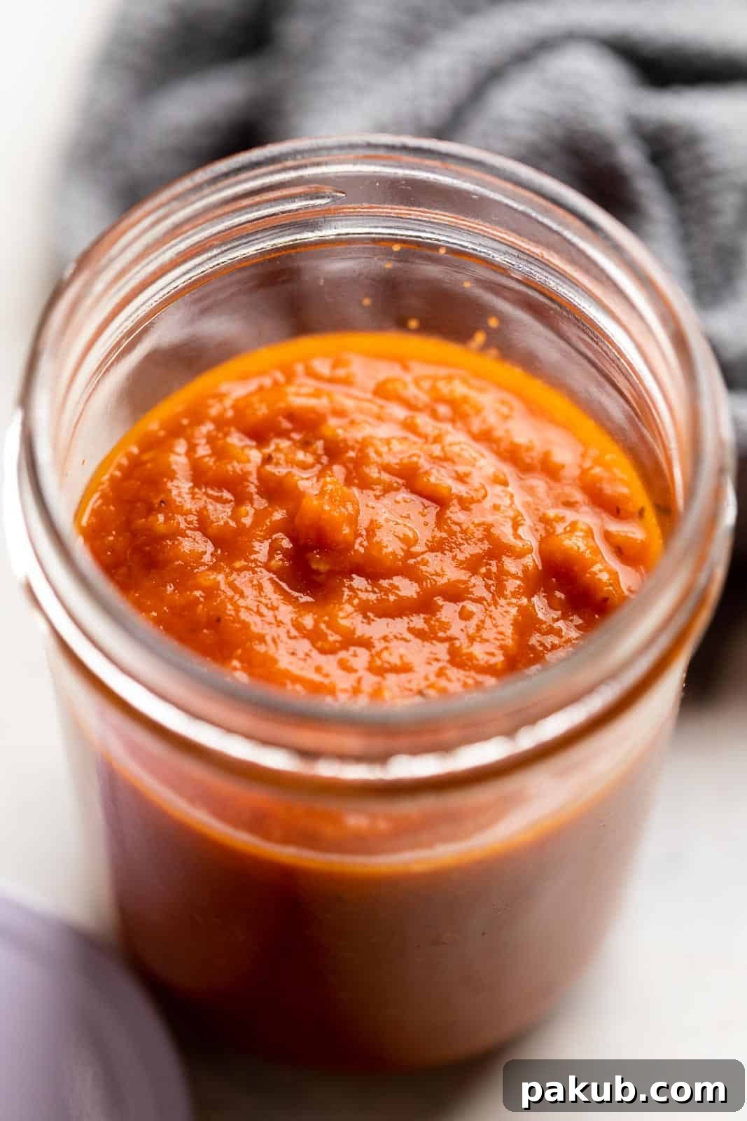 Easy Red Pasta Sauce 2 Rich, homemade red pasta and pizza sauce in a glass jar, perfectly cooked and ready for storage or immediate use.