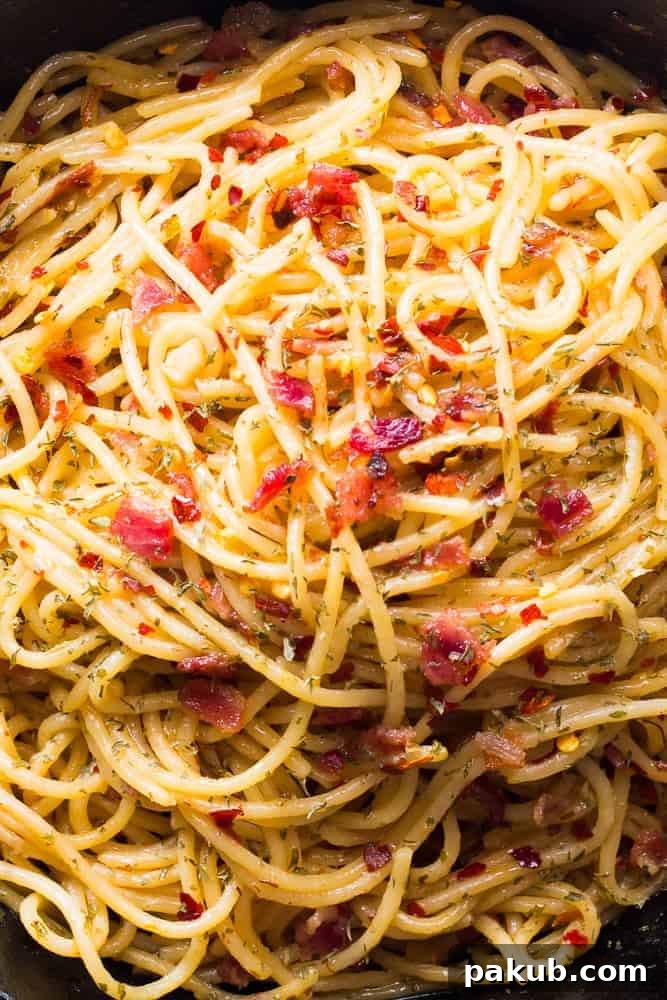 Detail of Bacon Spaghetti Aglio Olio Close up view of Bacon Spaghetti Aglio Olio showing crispy bacon bits and garlic slices.