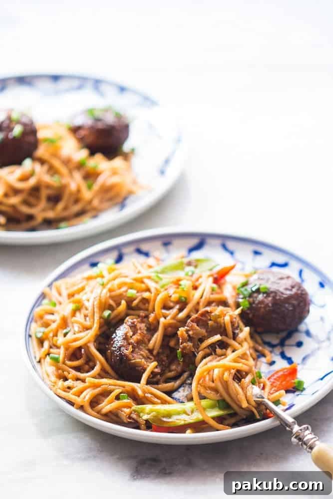 Ready to serve One-Pan Veg Noodle and Manchurian Stir Fry A serving of One-Pan Veg Noodle and Manchurian Stir Fry on a white plate with chopsticks.