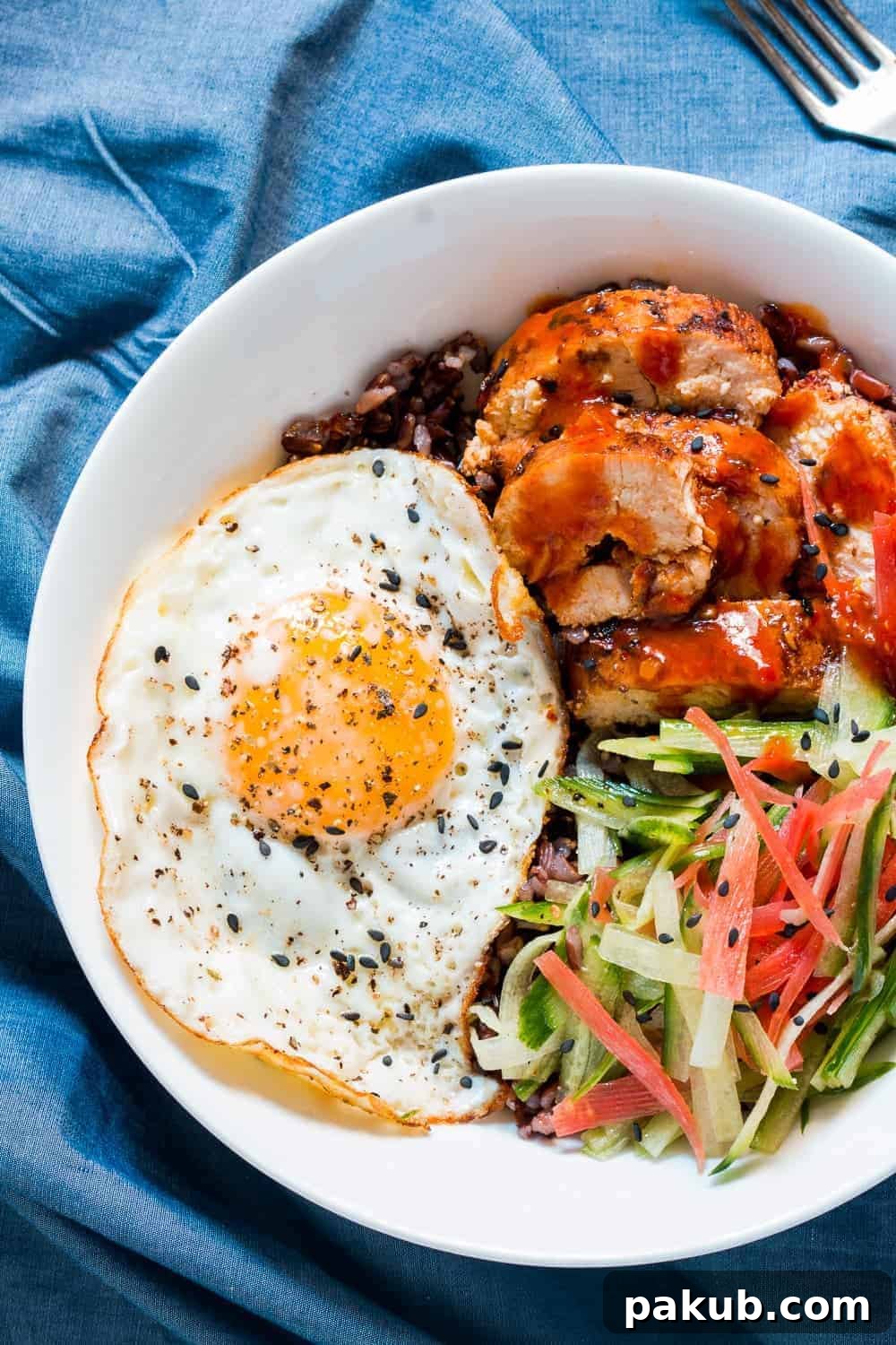 A beautifully presented Schezwan Chicken Bowl featuring tender chicken, fresh greens, and black rice.