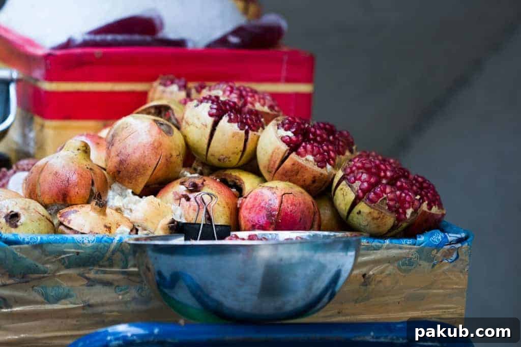 A street-side cart in Bangkok brimming with perfectly cut, glistening red pomegranates, ready to be served as a refreshing snack