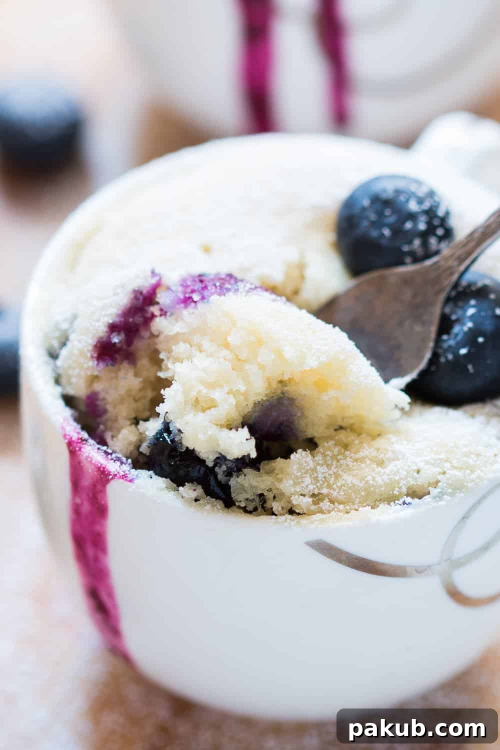 Close-up of a delectable bite from an eggless blueberry microwave mug cake, showcasing its soft texture