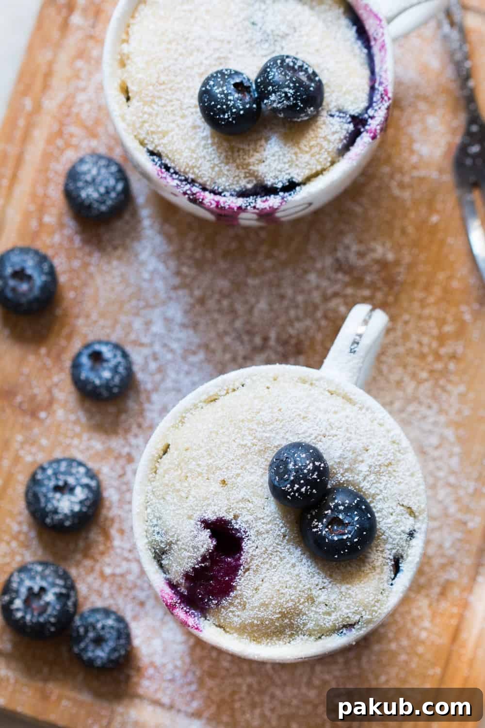 Beautifully cooked eggless blueberry mug cake, garnished with fresh berries and powdered sugar