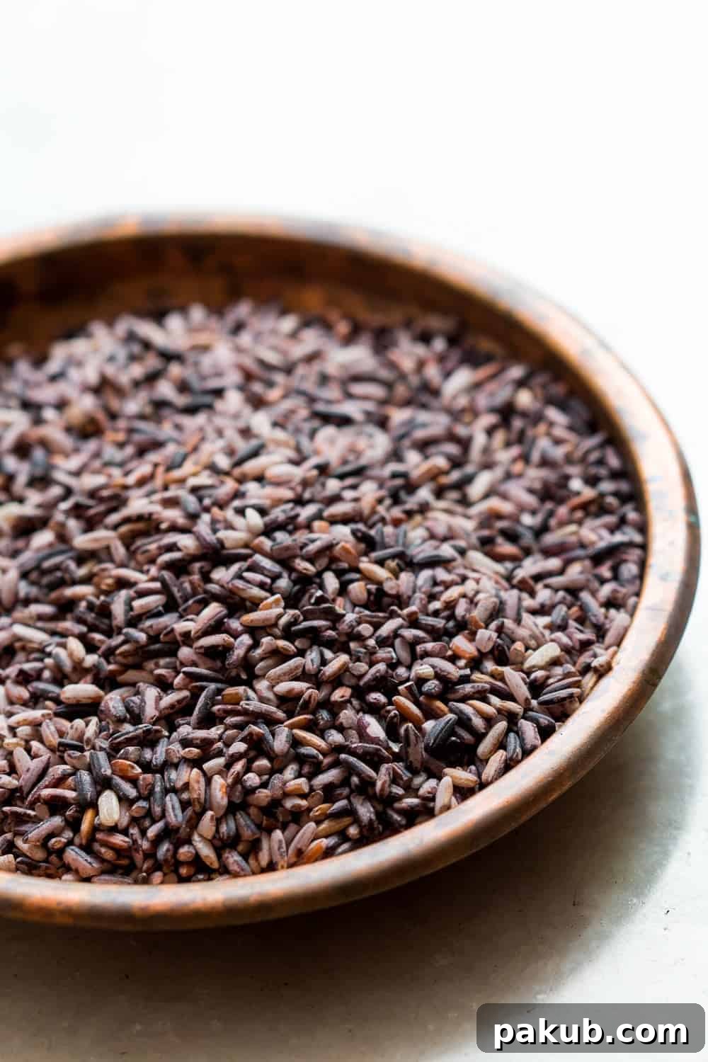 Uncooked Black Rice Grains Close-up shot of uncooked, raw black rice grains, showcasing their dark, rich color and glossy texture.