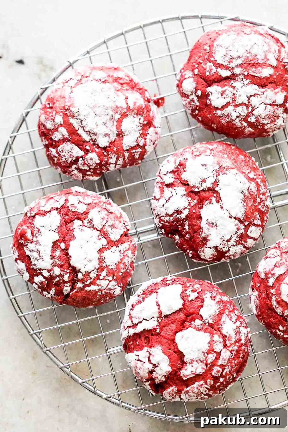 Freshly baked cakey red velvet cream cheese crinkle cookies cooling on a wire rack.