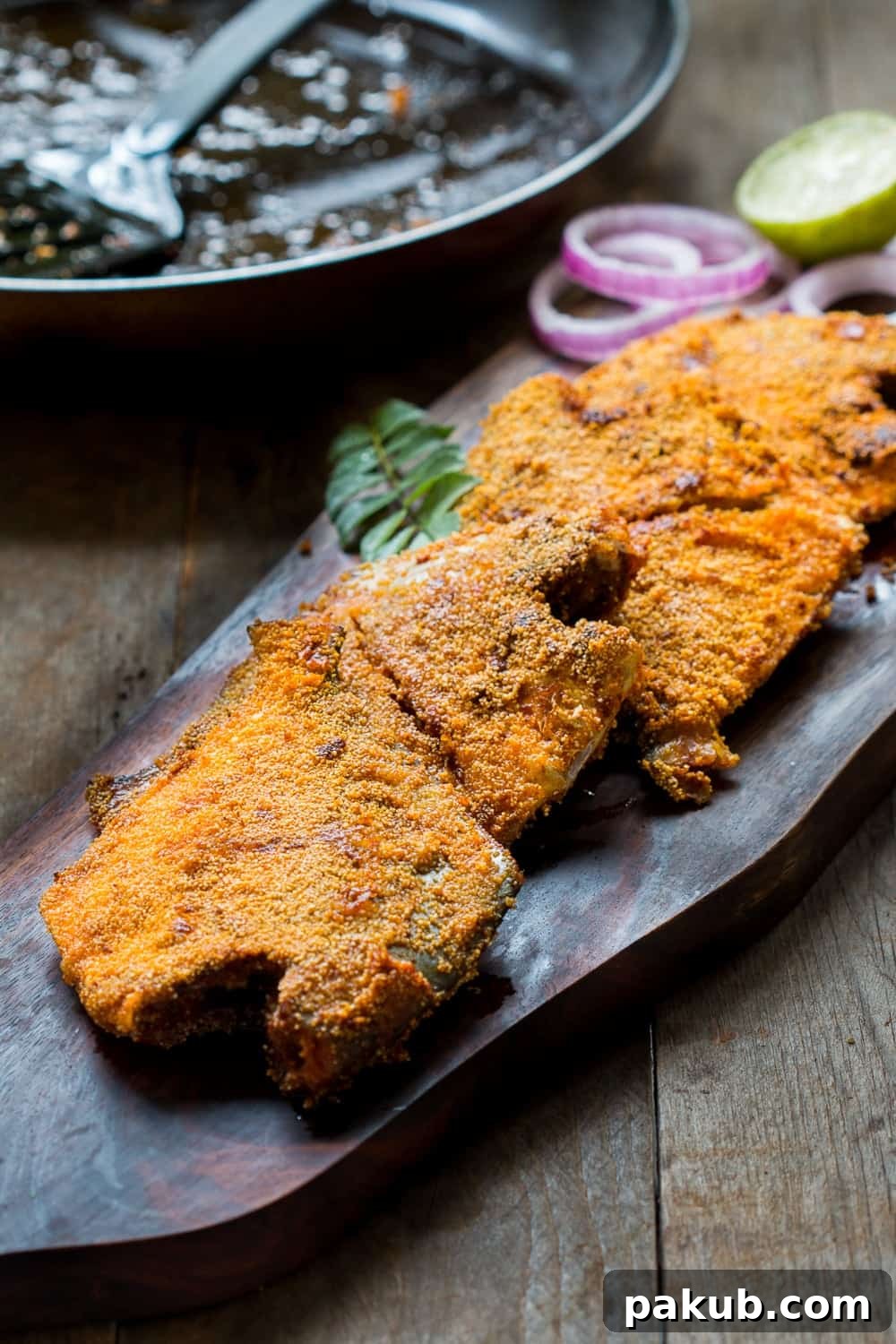 Mangalorean Pomfret Fry Presentation Serving of Mangalorean Rava Pomfret Fish Fry on a rustic wooden board with lemon wedges